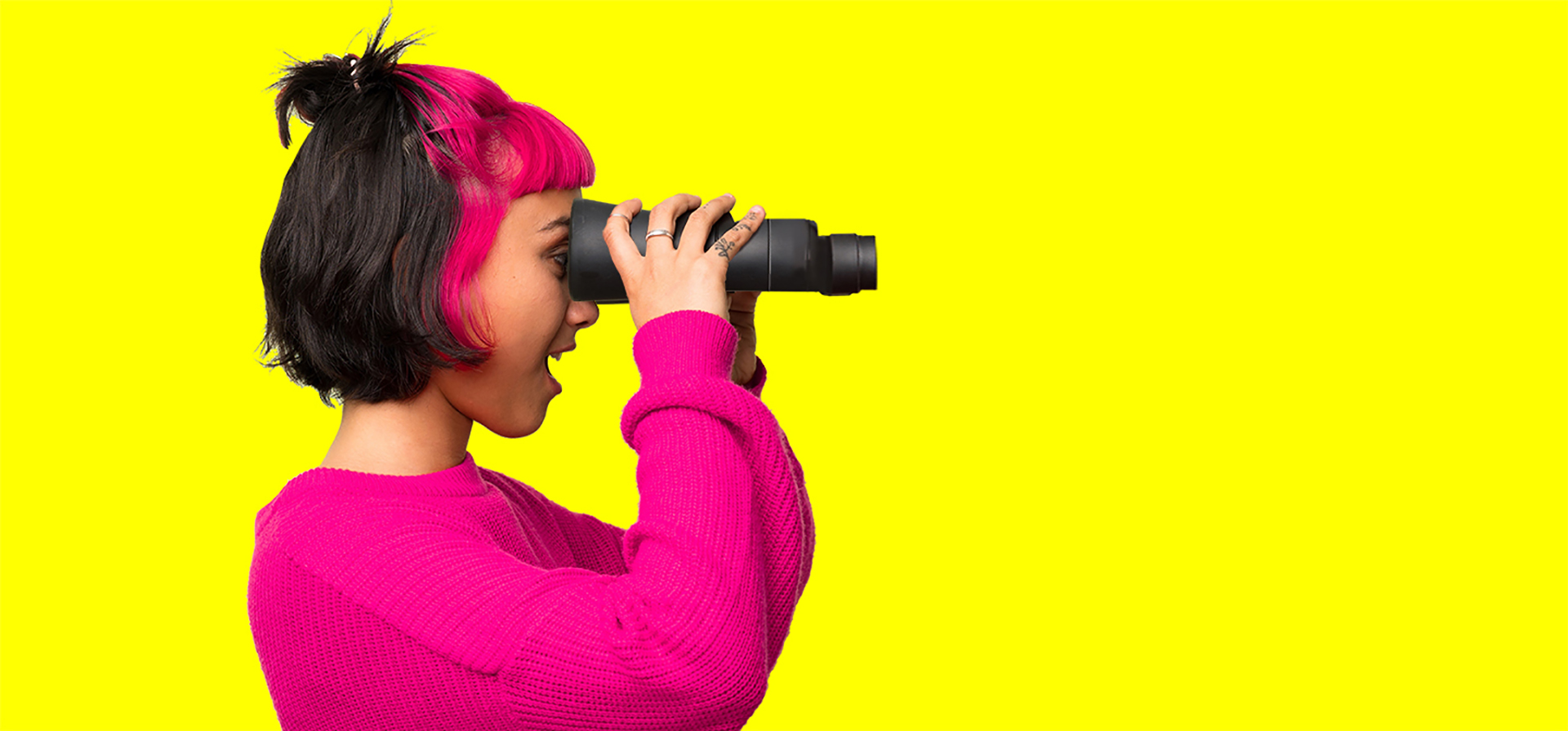 Young woman with red sweater and looking in the distance with binoculars